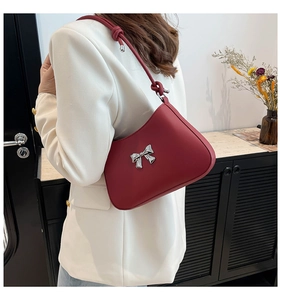 Vue latérale d'un sac sous le bras en cuir rouge vif avec boucle nœud argentée