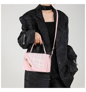 Détail d'un sac à main en tweed rose porté avec un manteau noir style élégant