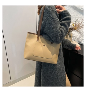 Détail d'un sac cabas beige avec fines lanières marron et poche extérieure porté par mannequin