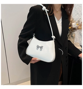 Détail du sac à bandoulière en similicuir blanc avec nœud argenté et bandoulière nouée