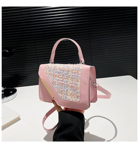 Détail du sac à main en tweed rose avec barre dorée et design à poignée supérieure
