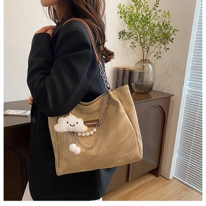 Détail du sac cabas beige avec chaîne en métal, bandoulière perle et charm nuage