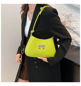 Détail du sac sous l'aisselle vert citron avec nœud en argent et bandoulière nouée
