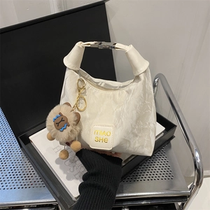 Chic cream quilted underarm bag with metal buckle handle and plush bear charm