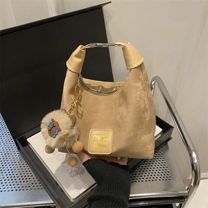 Minimalist beige dumpling tote bag with metal handle and plush charm for women