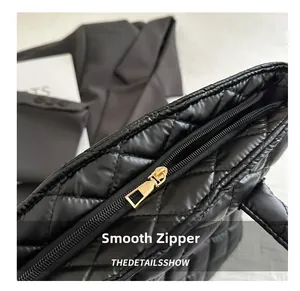 Primer plano de una cremallera dorada suave en un bolso tote negro acolchado