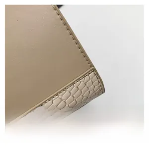 Macro shot of minimalist beige shoulder bag showing snake pattern leather and fine stitching
