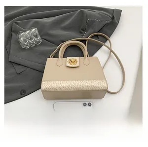 Detail view of cream leather crossbody bag with crocodile texture and gold floral lock