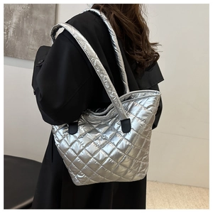 Primer plano del bolso tote plateado acolchado con acabado metálico y detalles de cuero