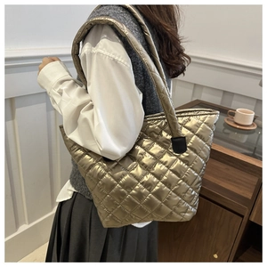 Detalle del bolso tote acolchado oro champán con textura suave y correa ancha acolchada