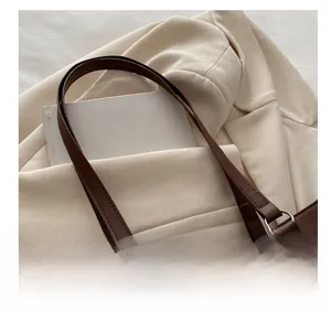 Detail shot of the long shoulder straps and silver metal ring on a dark brown tote bag