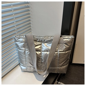 Detail der silbernen Metallic-Stepptasche mit gesteppter Textur und grauem Gurt