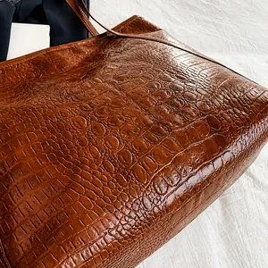Detail van de donkerbruine krokodillenreliëf op een stijlvolle leren shopper