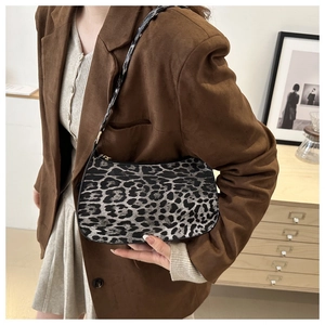 Leopard print underarm bag shown on model wearing a brown blazer in a minimalist setting