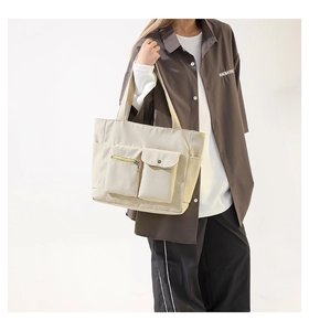 Detailed close-up showing the multi-pocket structure and durable beige nylon of the tote bag