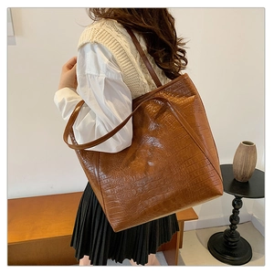 Detailweergave van bruine shopper met krokodillenprint en lange handvaten voor de schouder