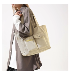 Close-up of a large nylon tote bag with multiple pockets worn by a model in cream white