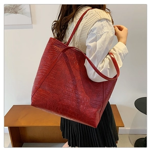 Detailopname van rode shopper met krokodillenprint op houten tuinbankje