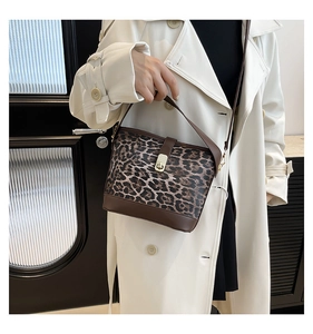 Detail of leopard print bucket bag featuring brown leather trim and gold twist lock