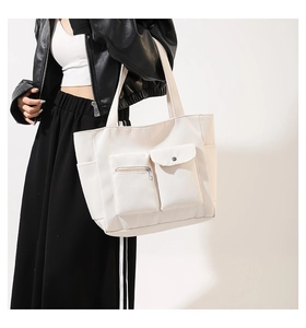 Side view of white nylon tote bag showing multiple pockets and spacious shoulder design