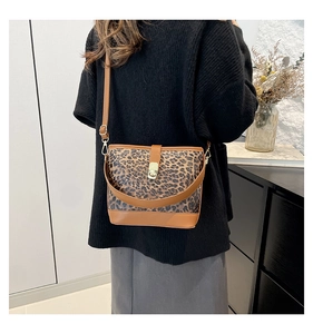 Detail of leopard print bucket bag with brown leather trim and golden metal rotary lock