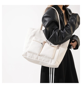 Detail of white nylon tote bag with functional cargo pockets and silver zipper