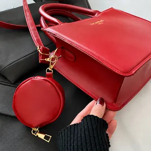 Dettaglio borsa a tracolla in pelle rossa con hardware dorato e un piccolo portamonete