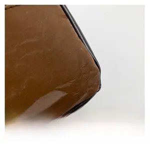 Close-up of deep brown glossy synthetic leather with natural wrinkled texture details