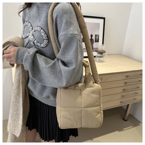 Dettaglio della borsa trapuntata beige con spallacci imbottiti e motivi a quadri grandi