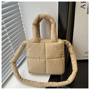 Dettaglio di una borsa trapuntata beige con trama morbida e tracolla in tinta abbinata