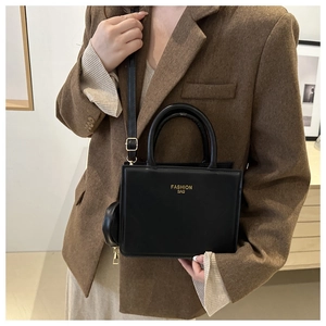 Detail of black crossbody bag with detachable round coin purse on a brown tweed blazer
