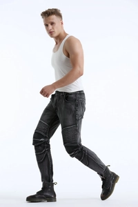 Detail of dark gray biker jeans with pleated knees and washed vintage denim texture