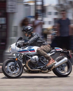 Dynamic side view of a rider in brown motorcycle riding jeans on a retro sports bike