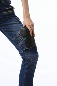 Macro detail of inserting flexible knee protectors into dark blue women's biker jeans