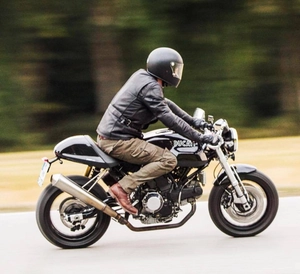 Full protective motorcycle riding gear set with vintage leather vest and helmet in motion