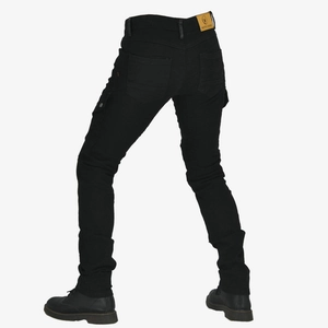 Detail view of black slim moto jeans featuring protective knee pleats and yellow leather patch