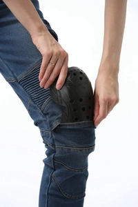 Detail of inserting black protective knee pads into green motorcycle denim riding pants