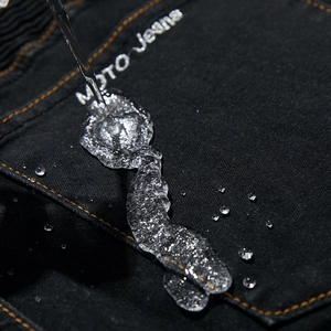 Waterproof denim detail of black moto jeans with water droplets on the back pocket