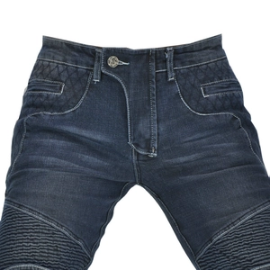 Macro detail of lion head embossed button and quilted stitching on moto riding jeans