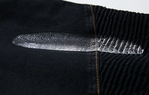 Macro view of waterproof denim fabric surface with water droplets and yellow stitching