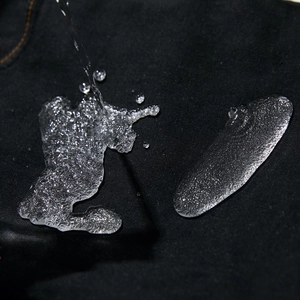 Detail shot of black motorcycle jeans with premium water-resistant fabric and droplets