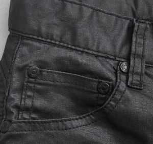 Close-up of black coated motorcycle jeans featuring metal rivets and reinforced stitching