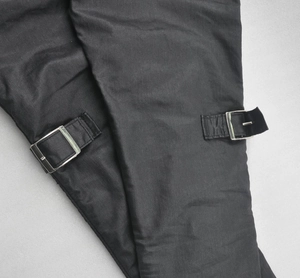 Detail of adjustable silver metal buckles on waterproof motorcycle jeans with black fabric