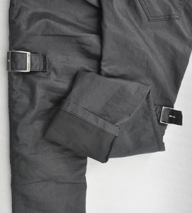 Close-up of waterproof riding pants with adjustable silver metal buckles and twill texture