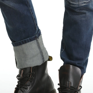 Detail of deep blue motorcycle jeans with rolled cuffs paired with black leather boots