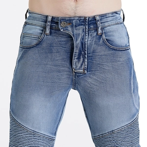 Detail of blue biker jeans featuring protective thigh pleats and washed metal button