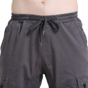 Detail of grey cargo pants featuring an elastic drawstring waist and large side pockets