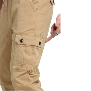 Detail of khaki cargo pants showing large side pocket with double black button closure