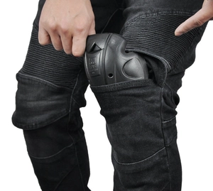 Detail of inserting CE certified removable knee pads into black motorcycle riding jeans