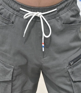 Detail of gray cargo motorcycle pants featuring elastic waistband and drawstring with metal zipper